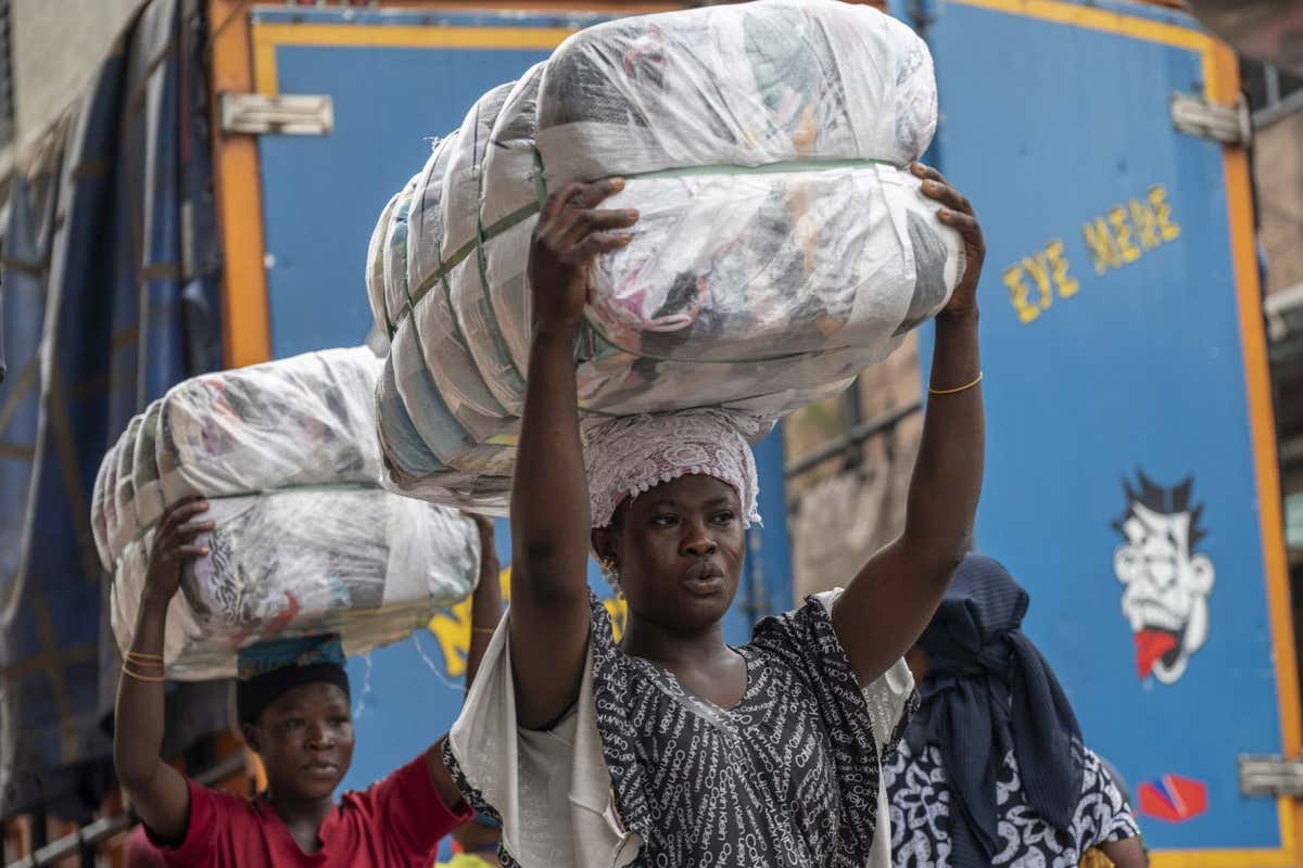 Female porters, known as 'kayayei', carry bales of second-hand garments on their heads at the Kantamanto textile market in Accra, Ghana, on Thursday, Sept. 15, 2022. The rise of fast fashionand shoppers preference for quantity over qualityhas led to a glut of low-value clothing that inordinately burdens developing countries. Photographer: Andrew Caballero-Reynolds/Bloomberg via Getty Images